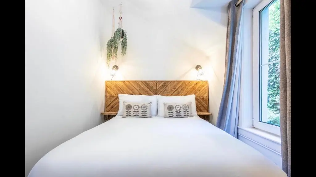 a white bed with two pillows and a window at Lamont Cottage in Inverness