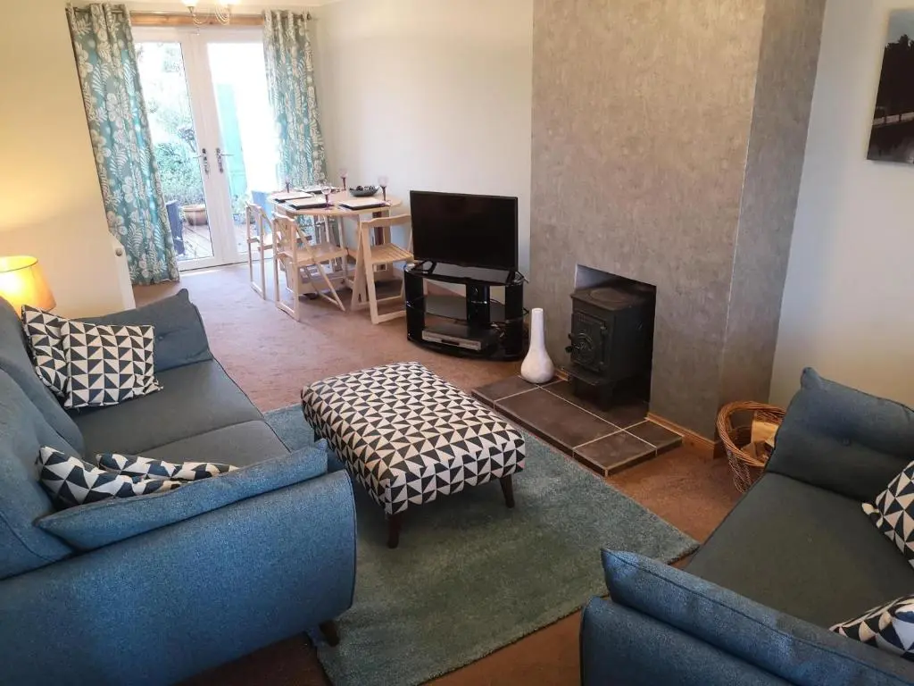a living room with two blue couches and a television at Highland Home From Home in Inverness