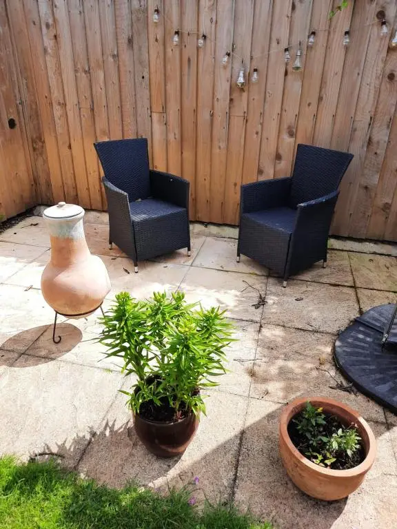 a patio with two chairs and a vase and plants at Highland Home From Home in Inverness