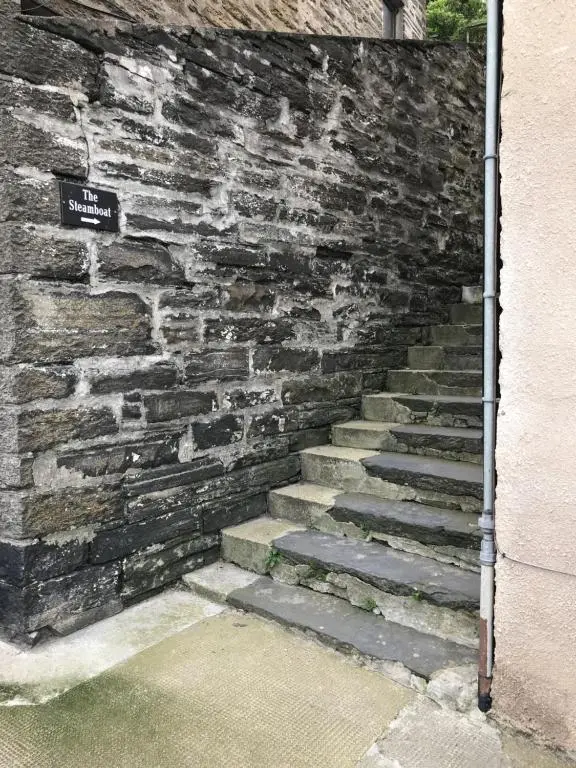a stone wall with a stone staircase next to a building at The Steamboat - A Flat with Amazing Harbour Views in Wick