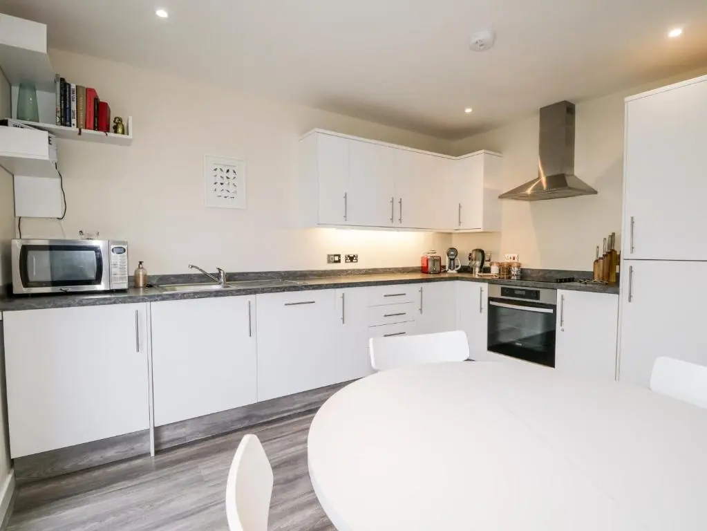 a kitchen with white cabinets and a white table at Skoglendi in Boat of Garten