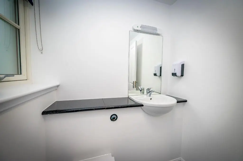 a white bathroom with a sink and a mirror at Loch Ness Bunk Inn in Drumnadrochit