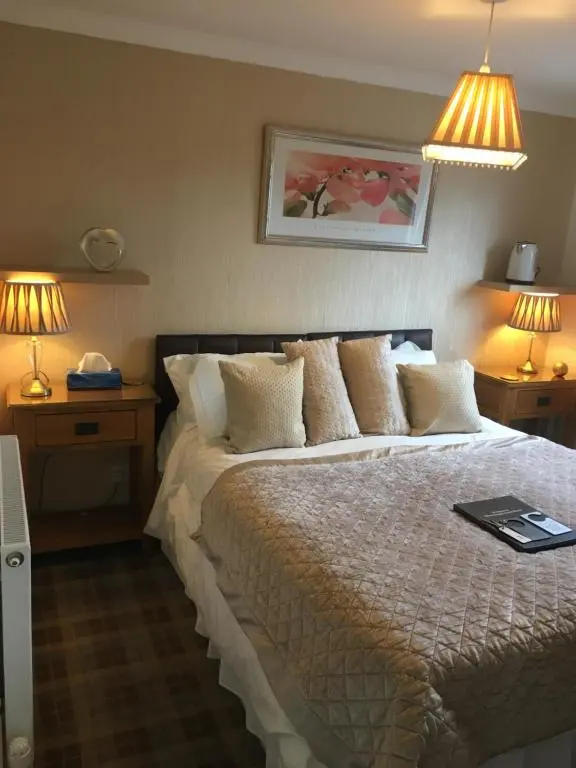 a bedroom with a bed with two lamps and two tables at Silverstrands in Inverness