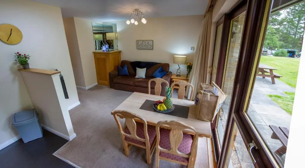 a living room with a table and chairs and a couch at Scandinavian Village Ltd in Aviemore