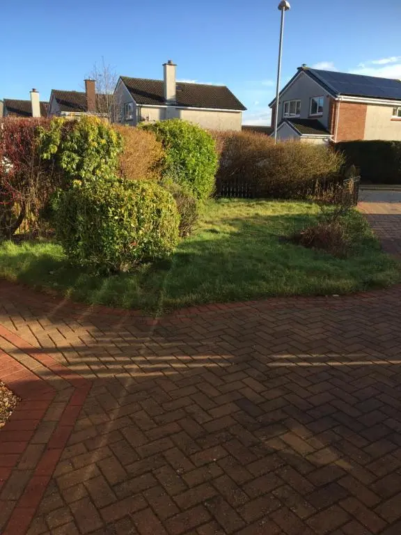 a brick driveway with green grass and bushes at Crescent Corner, Inverness in Inverness