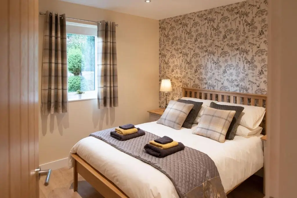a bedroom with a bed with two towels on it at Larchwood Lodge in Ellon