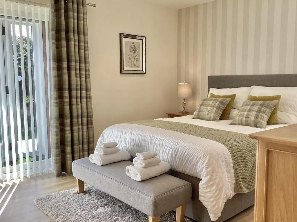 a bedroom with a large bed with towels on a bench at Larchwood Lodge in Ellon