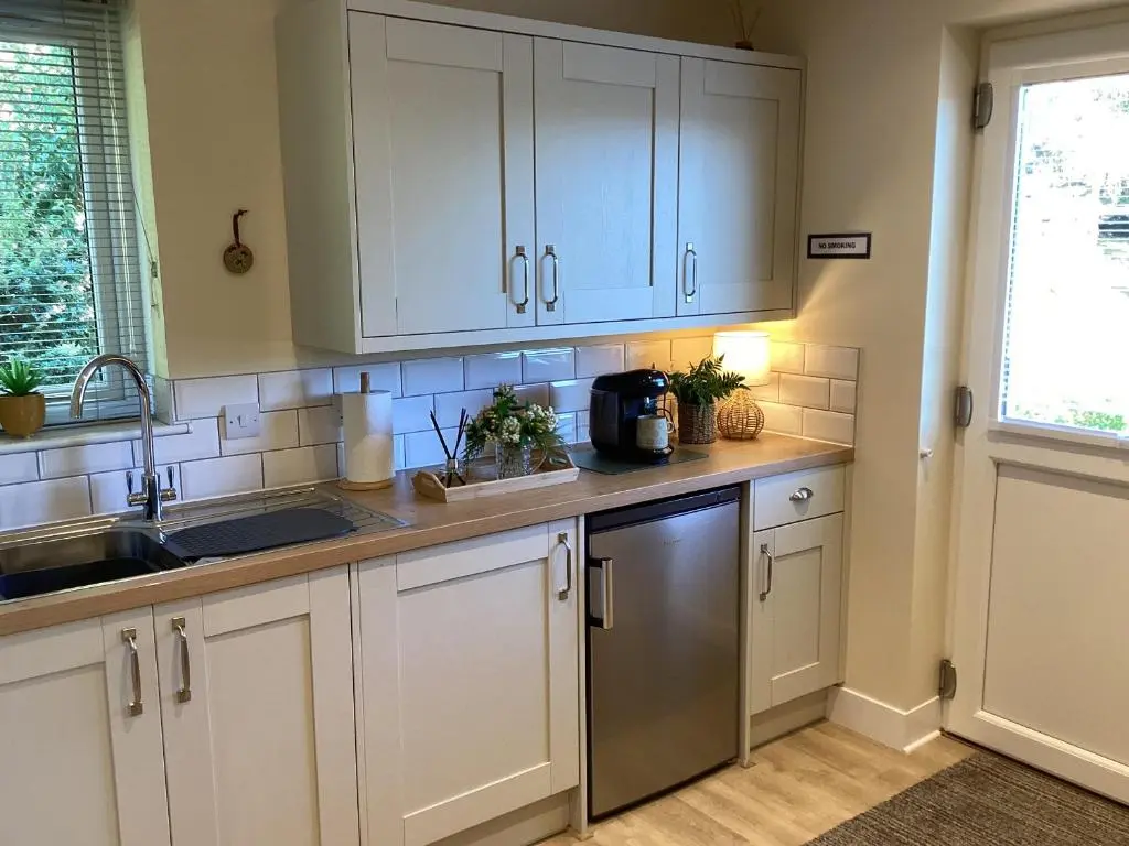 a kitchen with white cabinets and a sink and a window at Larchwood Lodge in Ellon