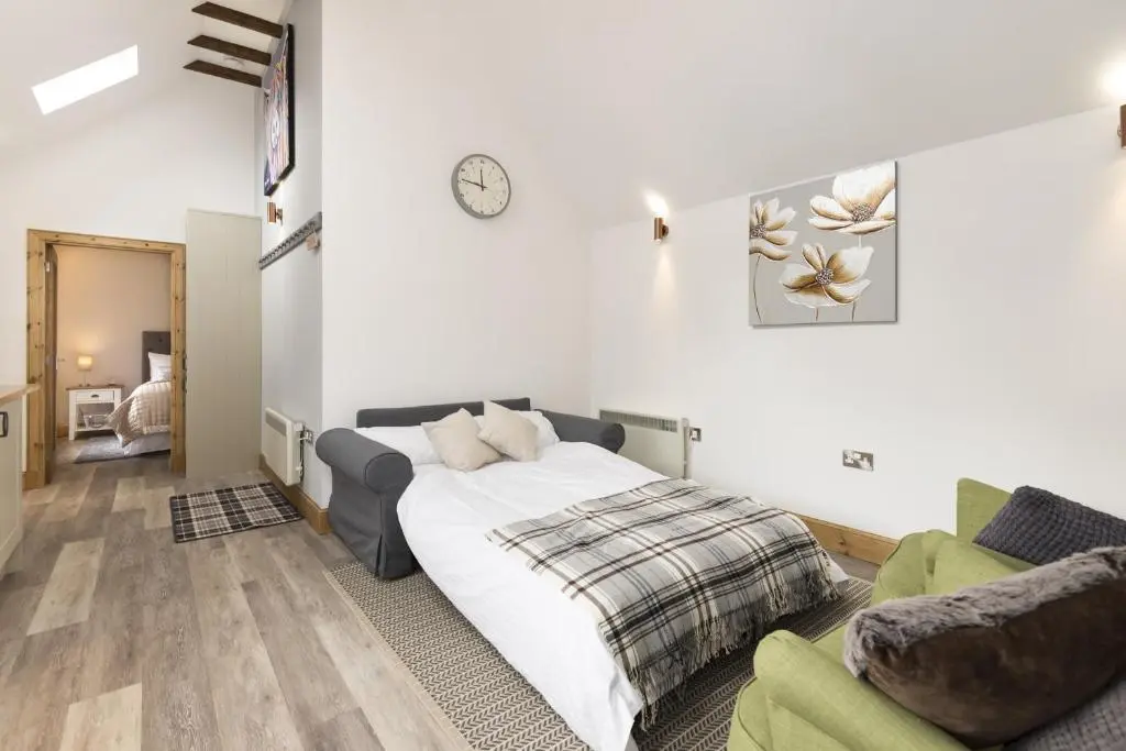 a bedroom with a bed and a couch at The Milking Sheds, Dufftown in Dufftown