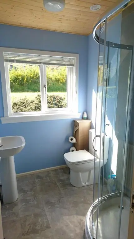 a blue bathroom with a toilet and a window at Craskie Glamping Pods in Inverness