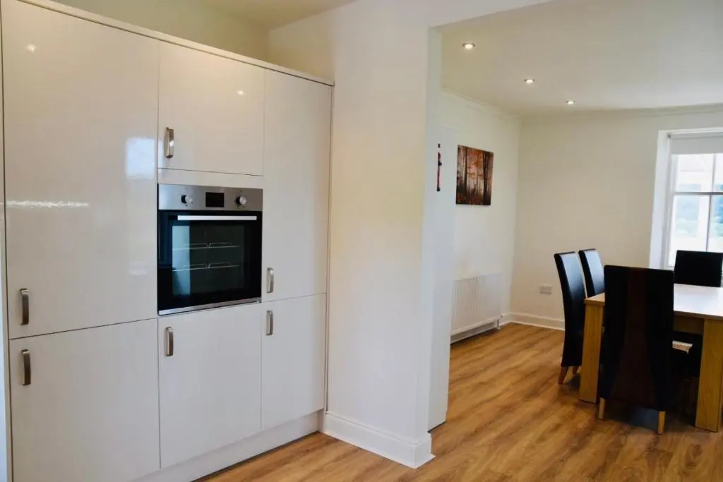 a kitchen with white cabinets and a table with chairs at Balintombuie in Dalchreichart