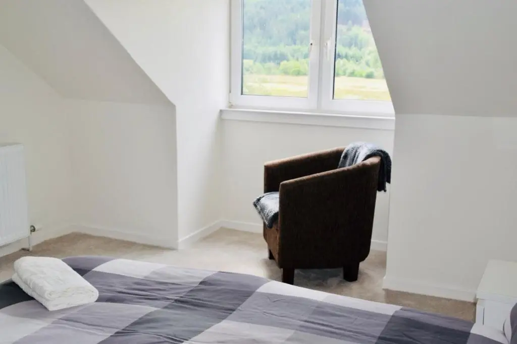 a bedroom with a bed and a chair and a window at Balintombuie in Dalchreichart