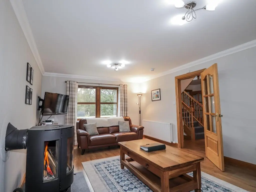a living room with a fireplace and a couch at Burnside House in Aviemore