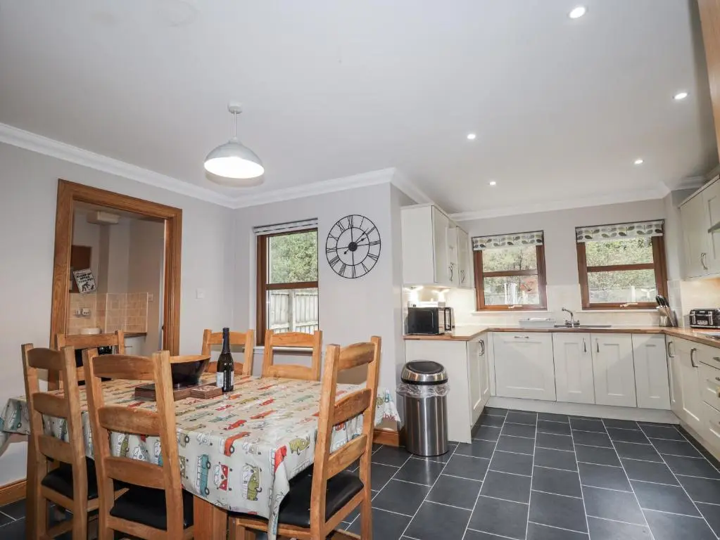 a kitchen with a table and chairs and a clock on the wall at Burnside House in Aviemore