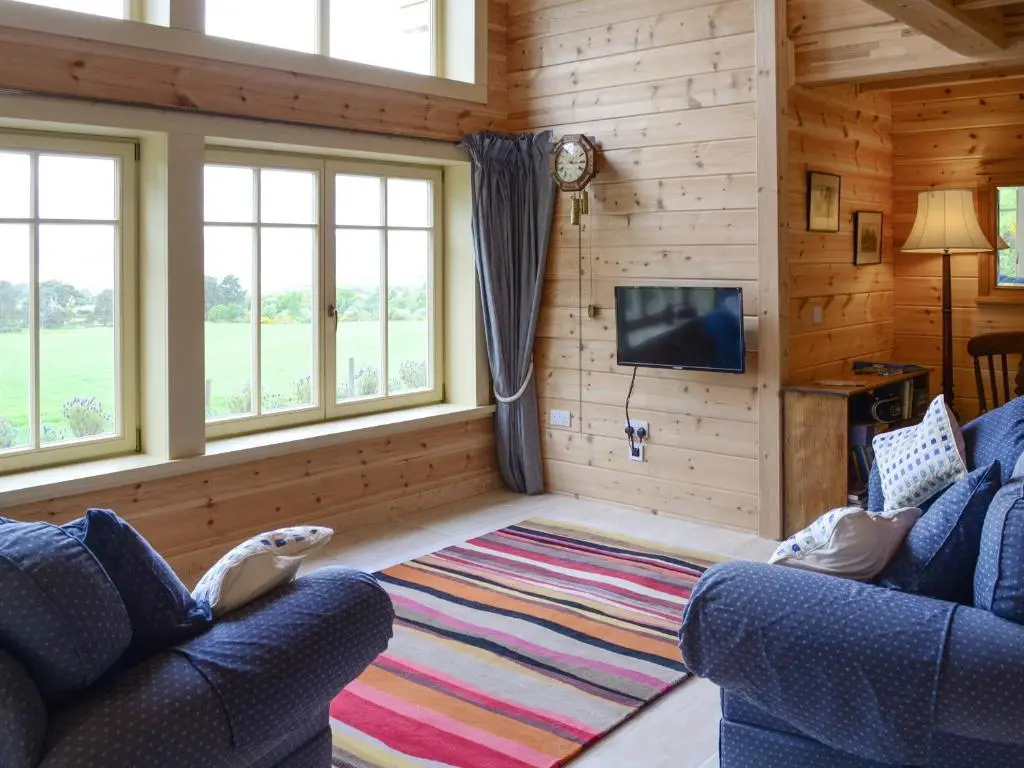 a living room with two blue couches and a television at Moonshine Cottage in Culbokie