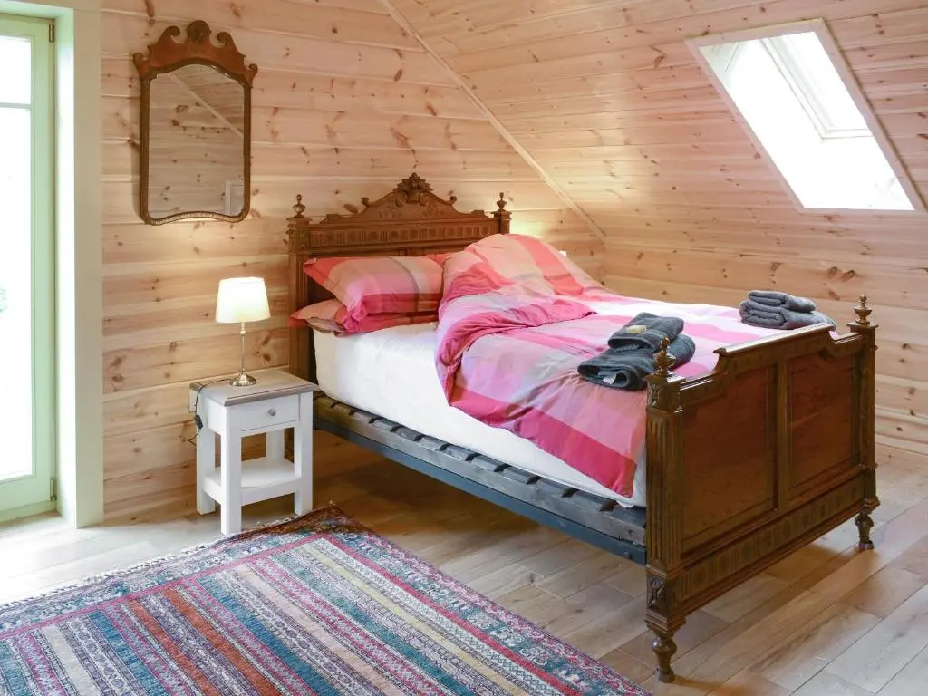 a bedroom with a bed in a log cabin at Moonshine Cottage in Culbokie