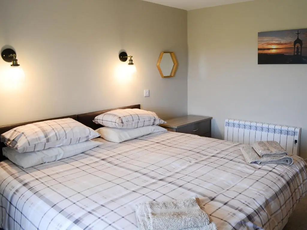 a bedroom with a bed with two pillows on it at Grieve's Cottage in Portmahomack