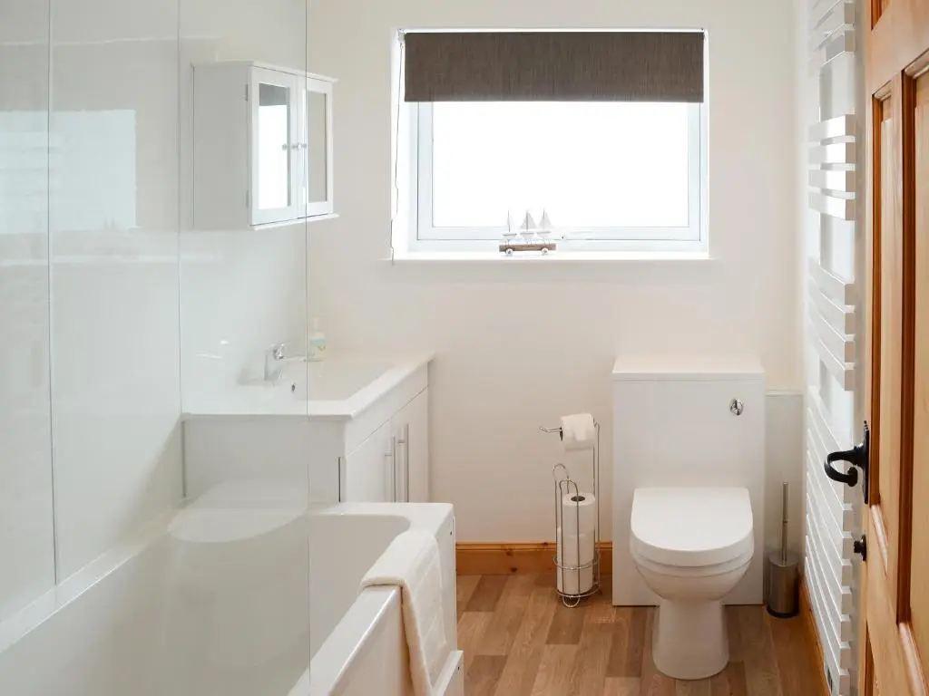 a white bathroom with a tub and a toilet at Grieve's Cottage in Portmahomack