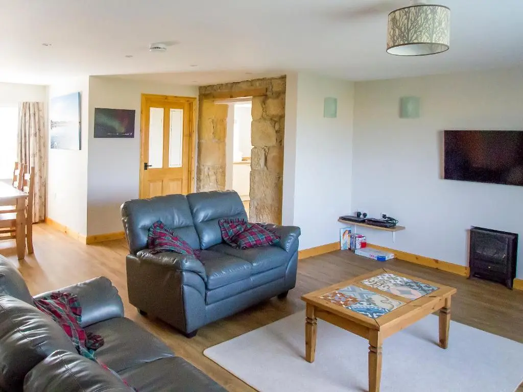 a living room with a leather couch and a coffee table at Grieve's Cottage in Portmahomack