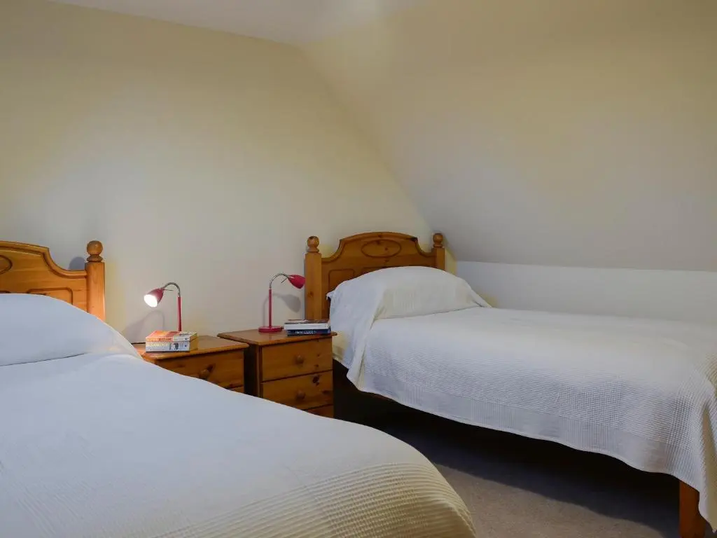 a bedroom with two beds and a table with lamps at Dairy Cottage in Whitehouse