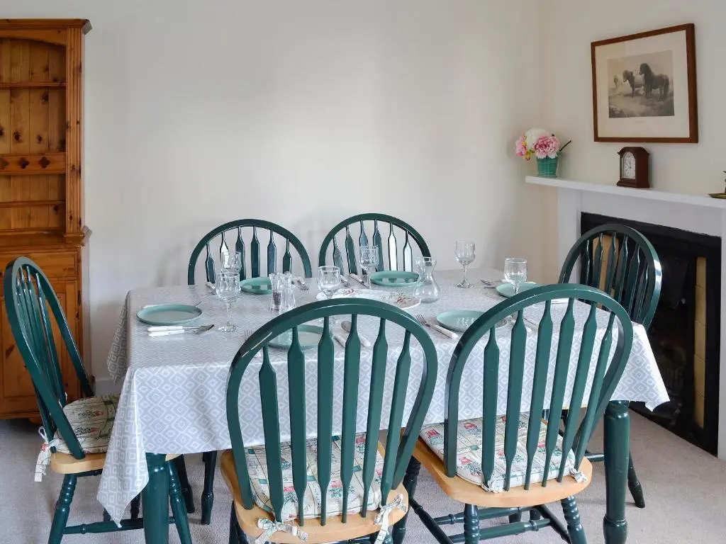 a dining room table with green chairs and a table with glasses at Dairy Cottage in Whitehouse
