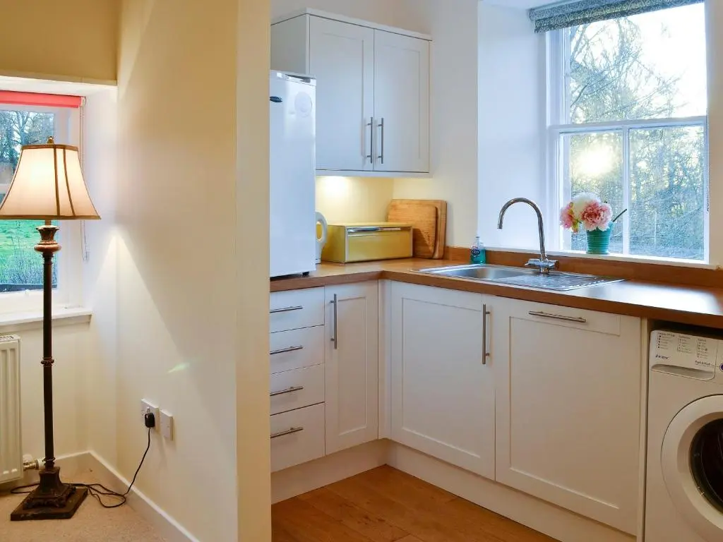 a kitchen with white cabinets and a sink at Dairy Cottage in Whitehouse