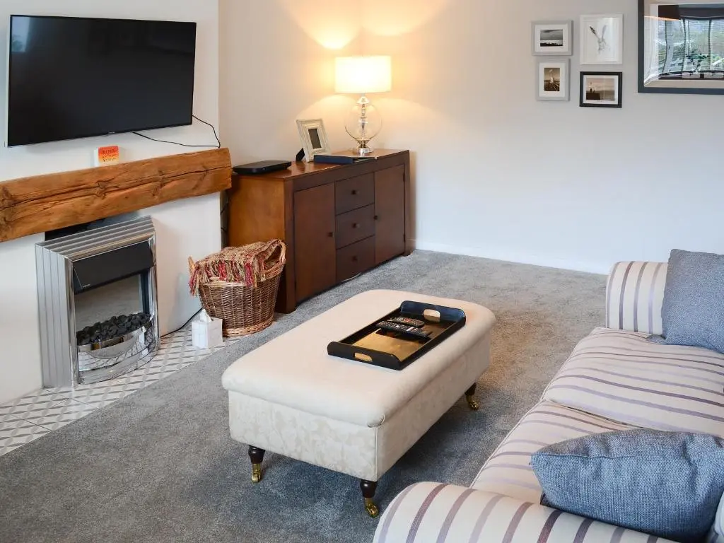 a living room with a couch and a tv at Sea Thistle Cottage in Nairn