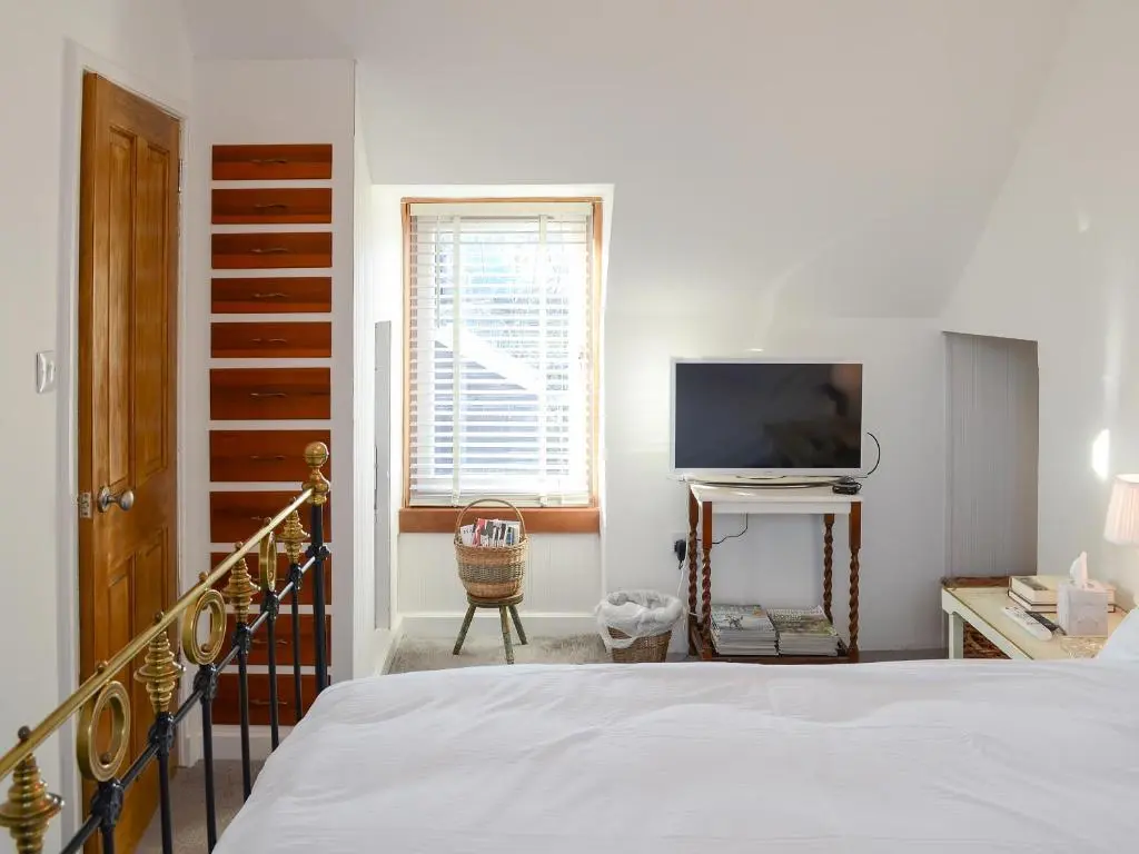 a bedroom with a bed and a flat screen tv at Sea Thistle Cottage in Nairn