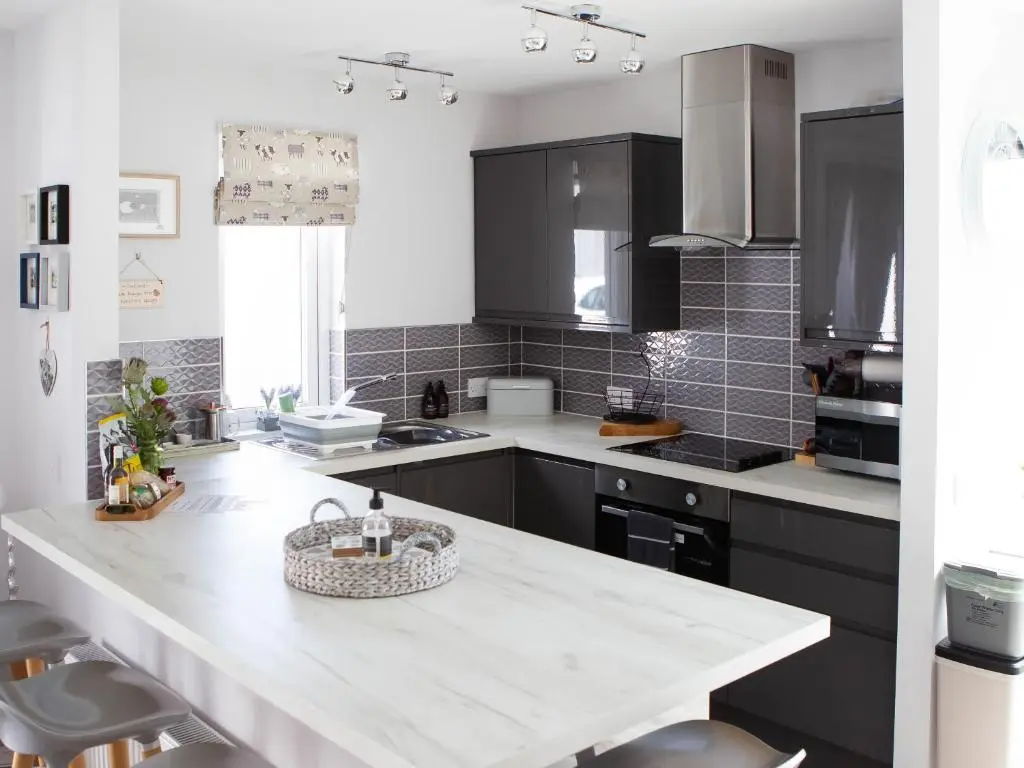 a kitchen with black cabinets and a white counter top at Rose Cottage in Dingwall