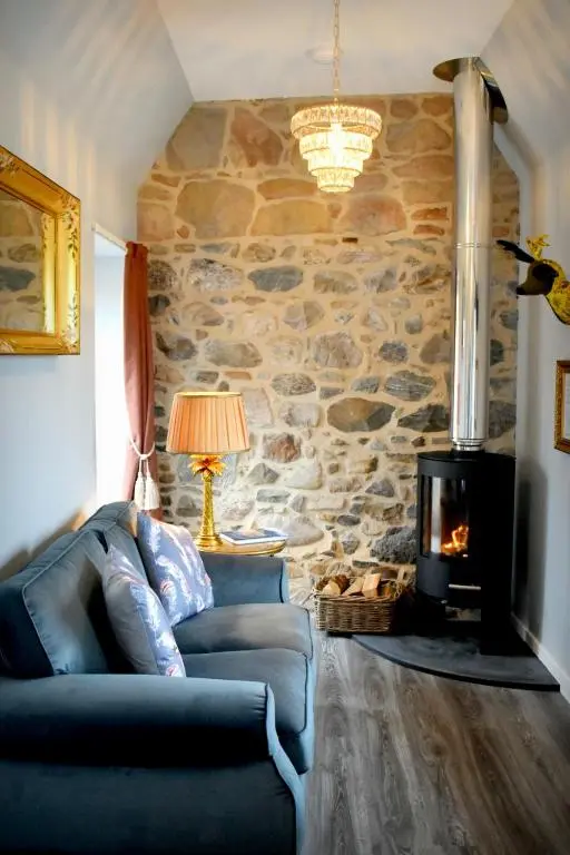 a living room with a couch and a stone wall at The Auld Reekie in Barbaraville
