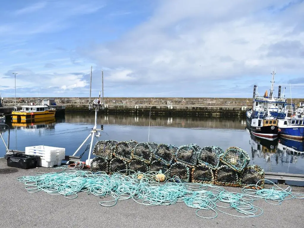 a pile of ropes on a dock with boats in the water at Sea Breeze Cottage in Buckie