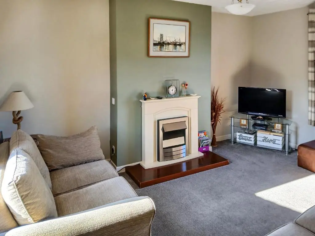 a living room with a couch and a fireplace at Sea Breeze Cottage in Buckie