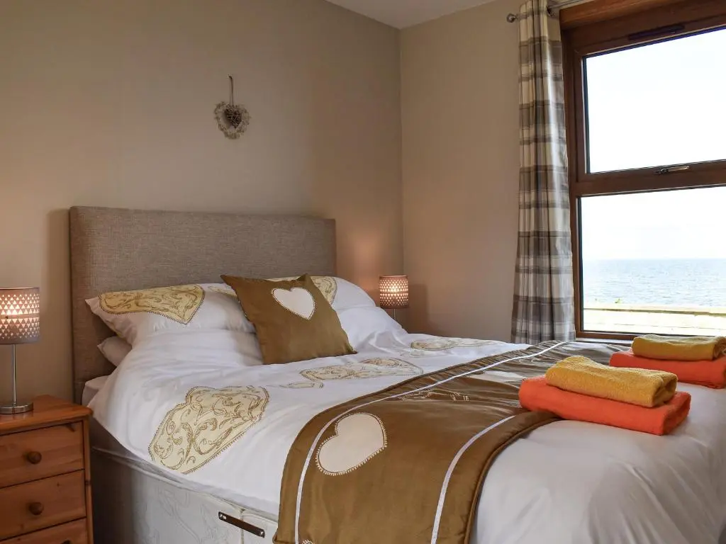 a bedroom with a bed and a window with the ocean at Sea Breeze Cottage in Buckie