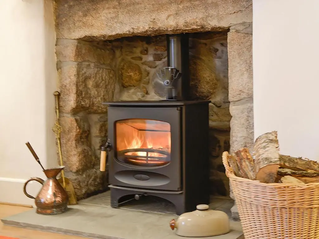 a wood stove sitting in a stone fireplace at Craigclunie in Ballater