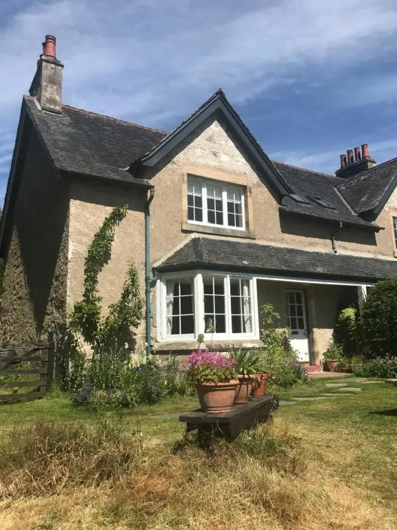 a house with a flower pot in the yard at Thistle Cottage, CrannachCottages in Garve