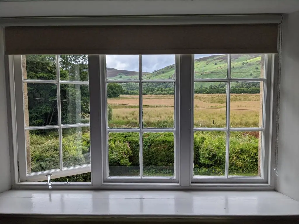 an open window with a view of a field at Thistle Cottage, CrannachCottages in Garve