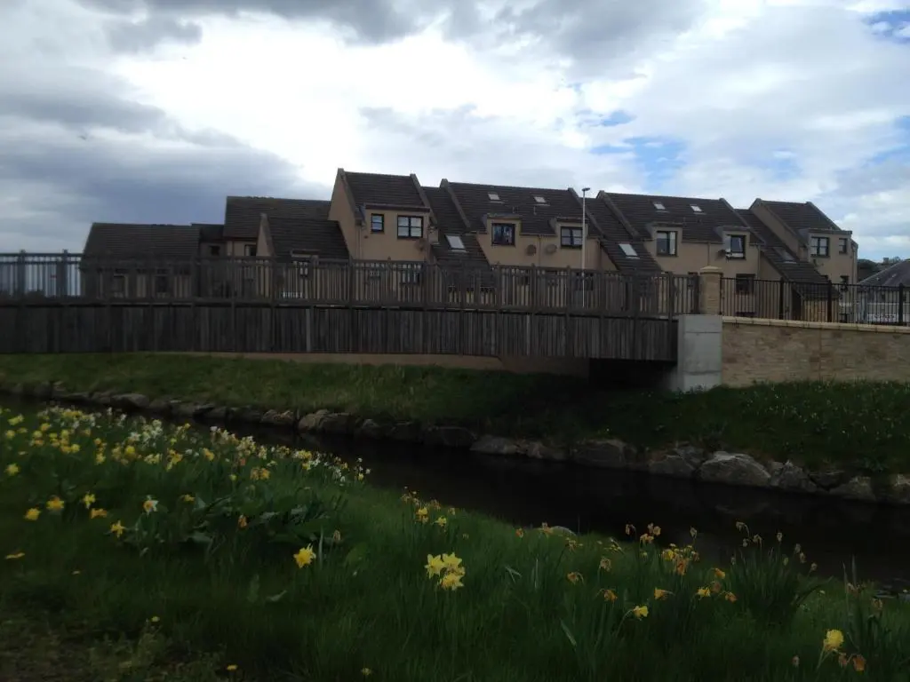a house on a bridge over a river with flowers at River View Apartment in Elgin