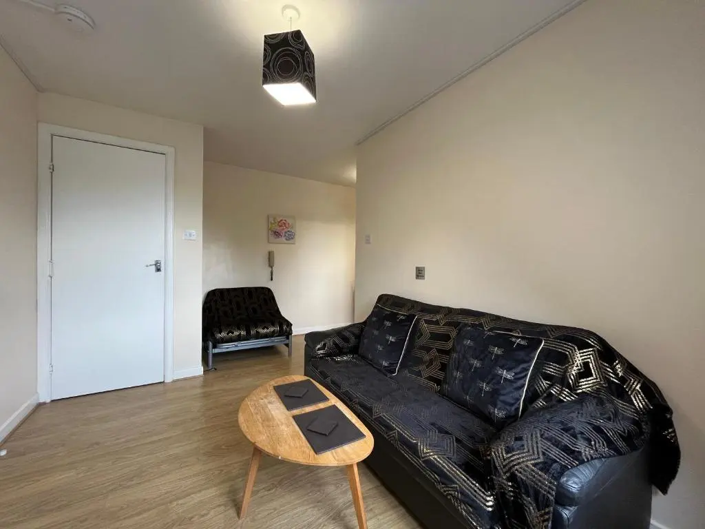 a living room with a black leather couch and a table at River View Apartment in Elgin