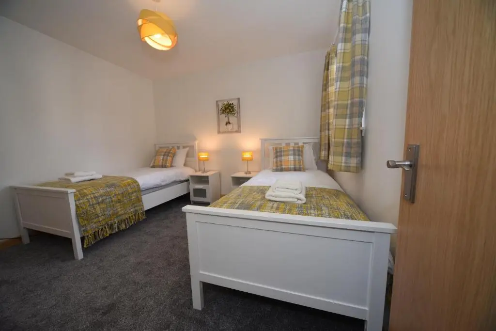 a bedroom with two beds and a table and a door at Silver Key Apartment 2 in Inverness