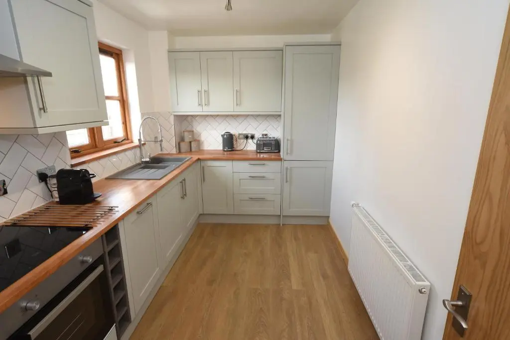 a kitchen with white cabinets and a wooden floor at Silver Key Apartment 2 in Inverness