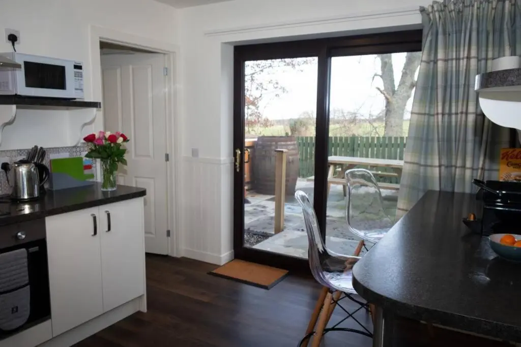 a kitchen with a table and chairs and a balcony at Drumossie Bothy in Inverness