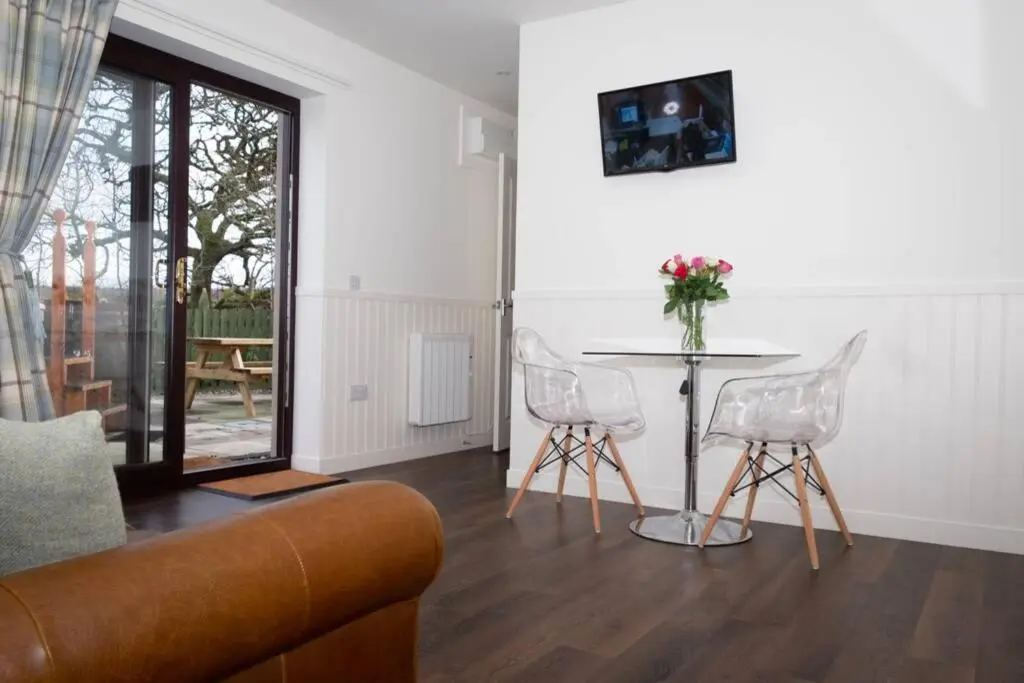 a living room with a couch and a table and chairs at Drumossie Bothy in Inverness