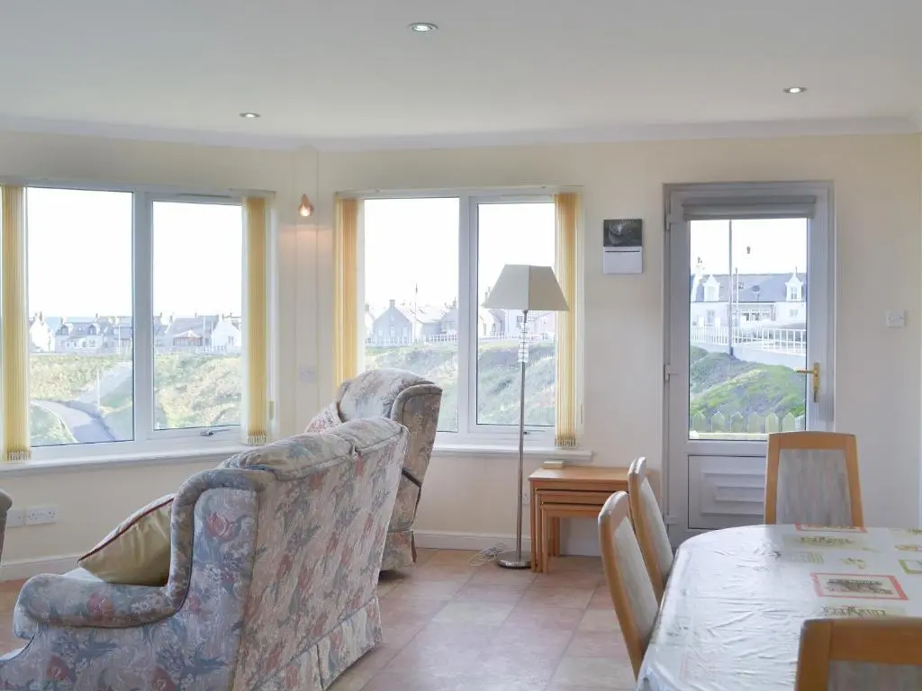 a living room with two chairs and a table and windows at White Gables - Uk30688 in Portknockie