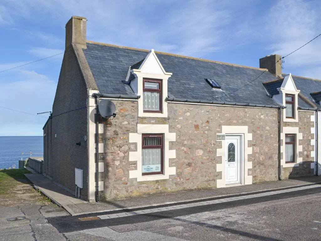 a stone house with the ocean in the background at Dolphin View - Uk30689 in Portknockie