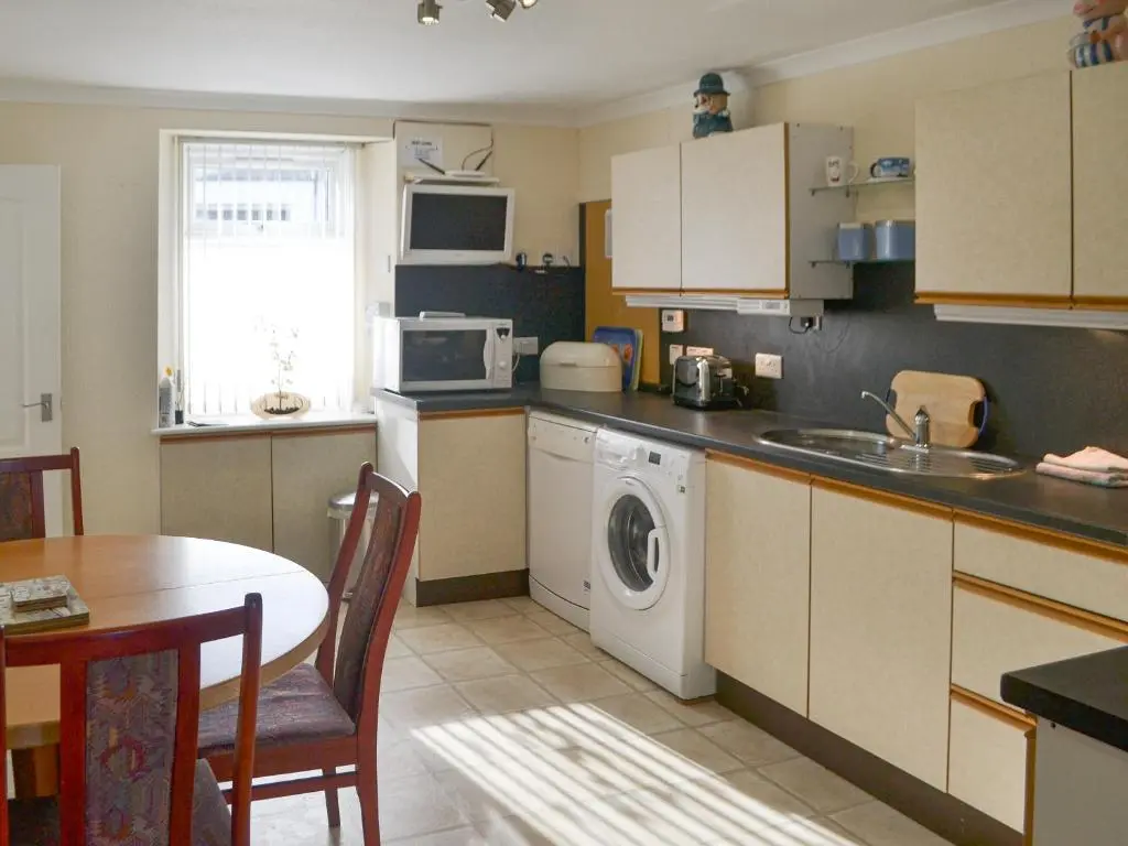 a kitchen with a washing machine and a table at Dolphin View - Uk30689 in Portknockie