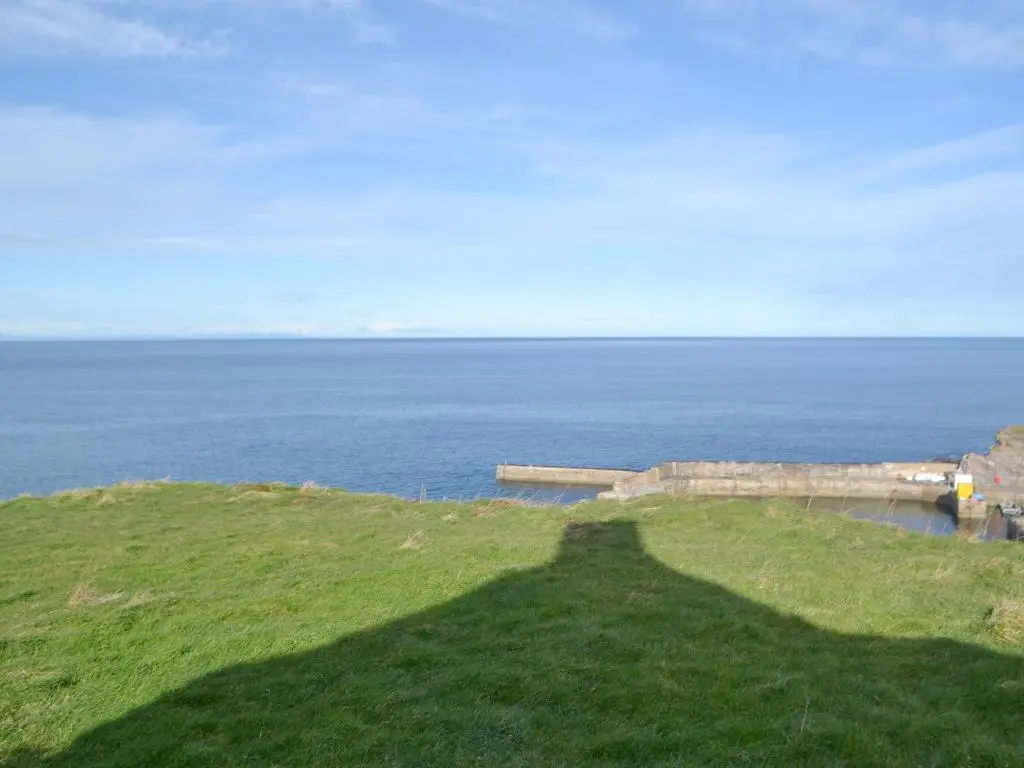 a grassy hill with the ocean in the background at Seabreezes - Uk30690 in Portknockie