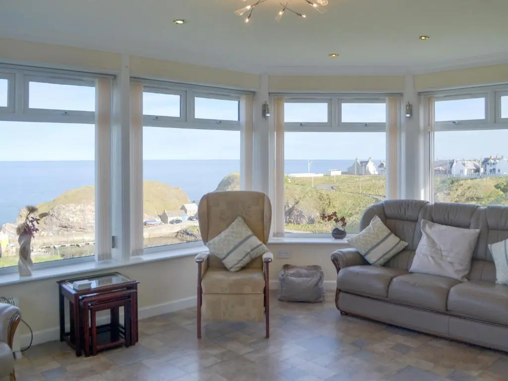 a living room with a couch and a chair and windows at Seabreezes - Uk30690 in Portknockie