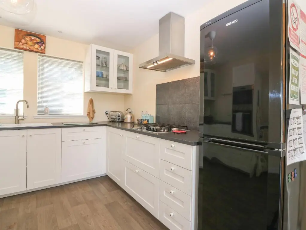 a kitchen with white cabinets and a black refrigerator at Berg Cottage in Ballindalloch