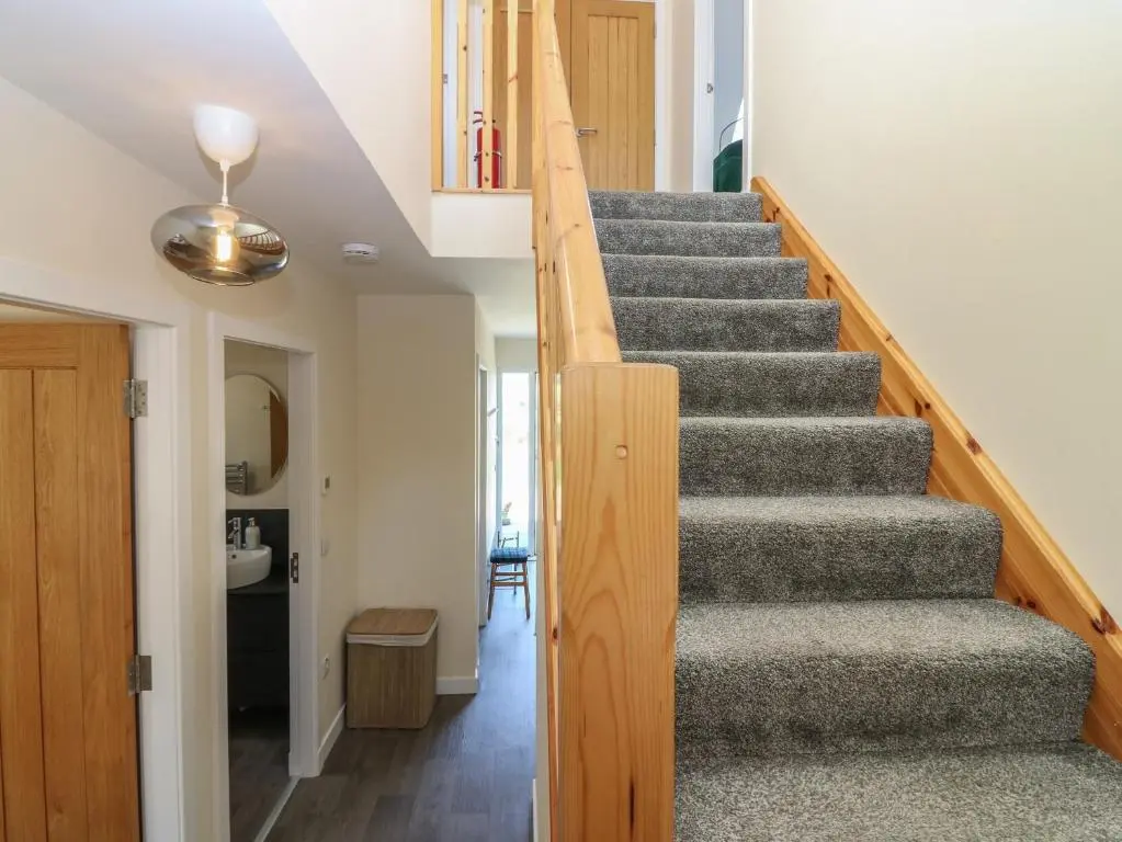 a staircase in a home with wooden railings at Berg Cottage in Ballindalloch