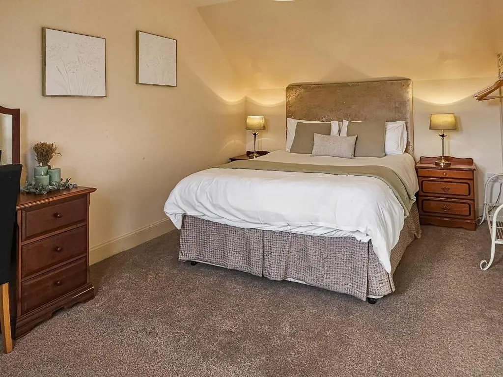 a bedroom with a large bed and two night stands at Balmore Farmhouse in Lochend